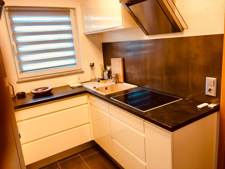 Cucina con lavello, piano in vetroceramica, top scuro e finestra
