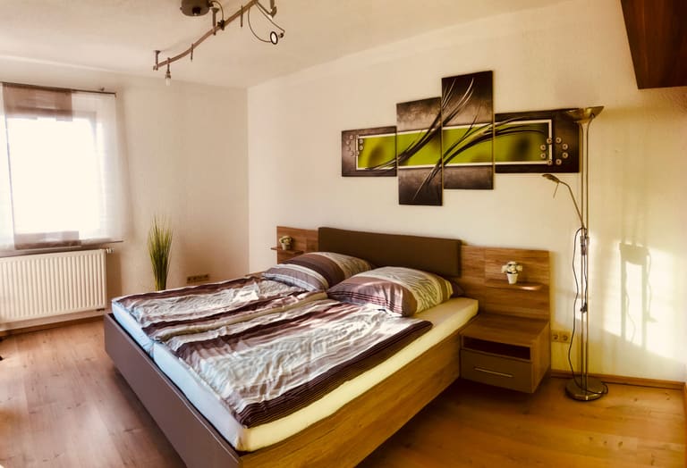 Camera da letto con letto matrimoniale, comodini e finestra affacciata sul verde