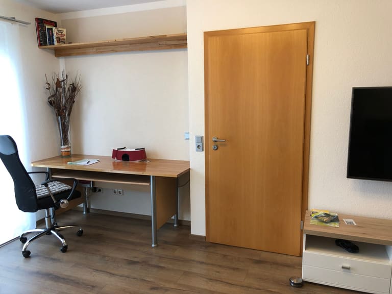 Desk with office chair and wall shelf, with the television alongside